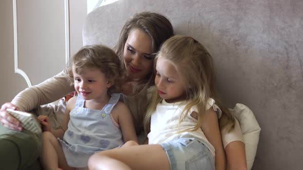 Family With Phone. Woman And Children Using Phone At Bedroom