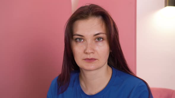 Woman is Sitting on an Armchair Looking at Camera Without Emotion Showing Off