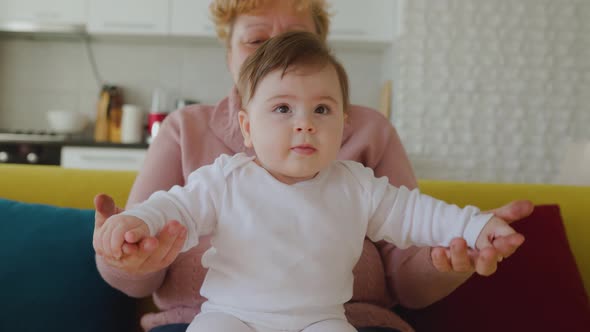 Happy Caucasian Grandmother Playing and Holding Her Little Granddaughter at Home