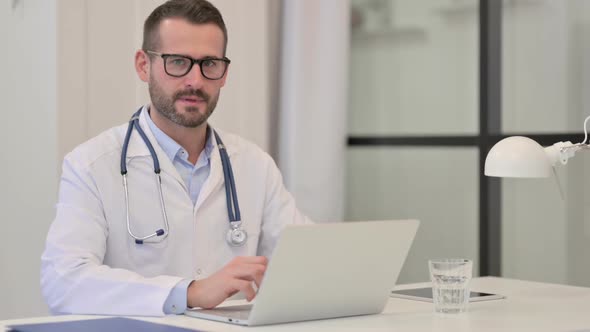 Male Doctor with Laptop Looking at the Camera in Hospital