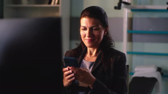 Positive Female Employee with Eye Patches Using Cellphone