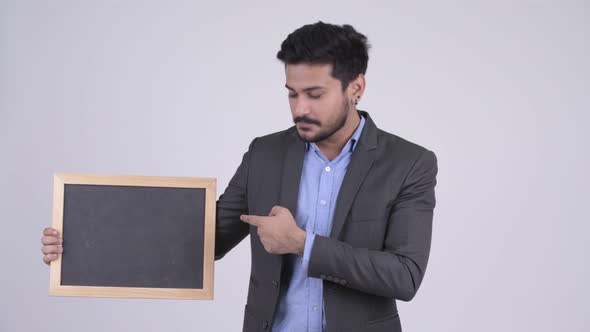 Young Happy Bearded Indian Businessman Showing Blackboard and Giving Thumbs Up