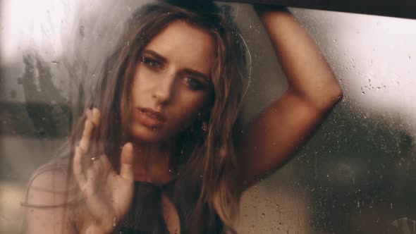 Fashion and Beauty. Window with Water Drops Before Closed Girl with Makeup. Rain Drops on Window