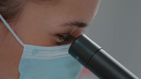 Biologist with Face Mask Using Microscopic Lens on Chemistry Tool