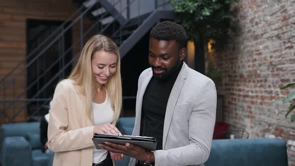 Blond Female Worker and Bearded African American Businessman Using I-pad