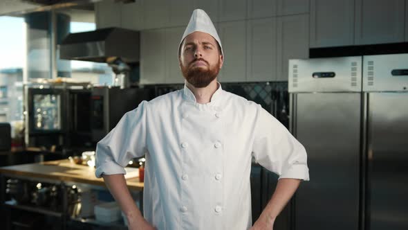 Professional kitchen, portrait: Male Chef folds his arms and looks at the camera