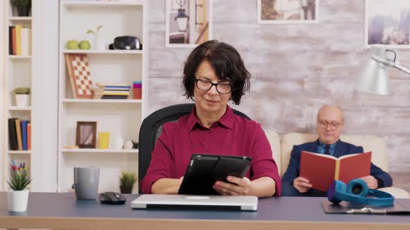 Elderly Woman with Glasses Using Tablet in Living Room