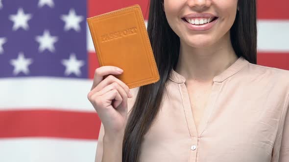 Smiling Woman Showing Passport Against American Flag, Getting USA Citizenship