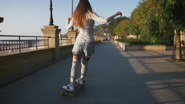 Young Stylish Attractive Woman Skateboarding at Sunrise on Seafront Slow Motion