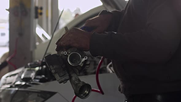 Mechanic Checking Car's Defective Turbocharger At Car Repair Shop