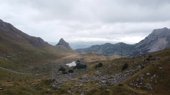 Hilly Valley with Stones and Small Pond Between the Mountains