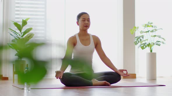 Calm of Attractive Asian woman practice yoga lotus pose to meditation in bedroom