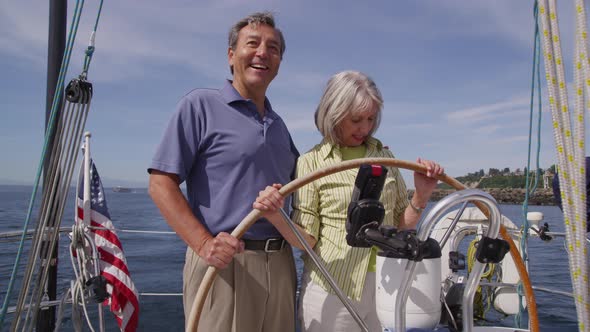 Senior couple behind the wheel of sailboat together. Shot on RED EPIC for high quality 4K, UHD, Ultr