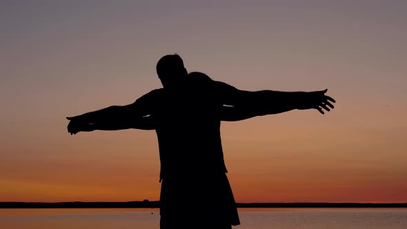 Silhouette Couple In Love At Sunset Take Each Others Hands And Raised To Side