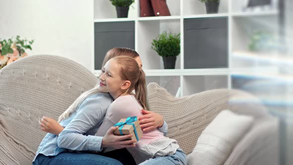 Little Cute Girl Smiling Giving Gift Box to Happy Mom Congratulation Celebrating Mother Day