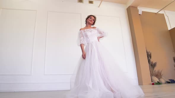 The Bride in a White Dress Poses for the Photographer Standing Spinning