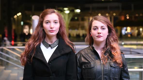 Two young women friends outdoor looking camera serious serene