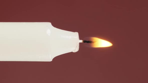 A Single Candle Is Lit on a Red Background. Light and Extinguish the Candle