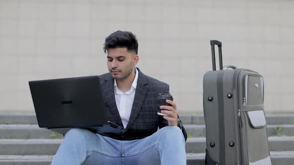 Young Handsome Bearded Asian Indian Man in Smart Casual Clothes with Wireless Laptop Sitting on