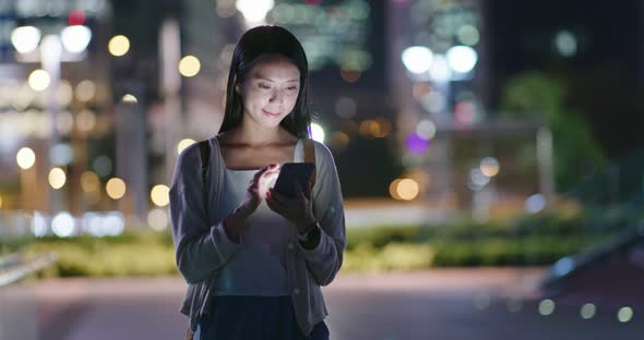 Woman use of mobile phone in city at night