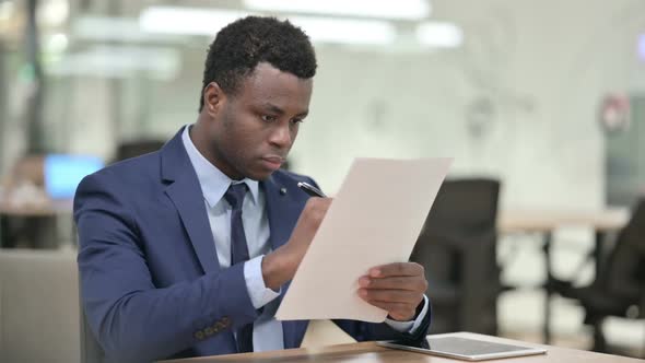 African Businessman Reading Documents in Office