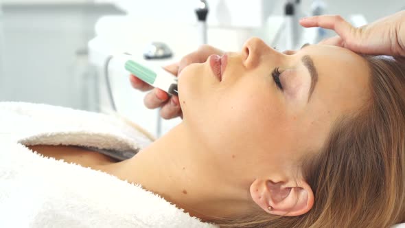 Cosmetologist Using Ultrasonic Scrubber on Client's Face