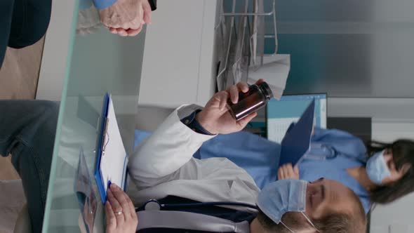 Vertical Video Male Physician Explaining Medicine in Bottle of Pills to Old Man