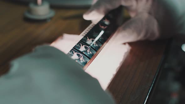 Detail of a film strip in the hands of a man with white gloves who checks the frames.