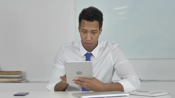 AfroAmerican Businessman Surprised By Results While Using Tablet
