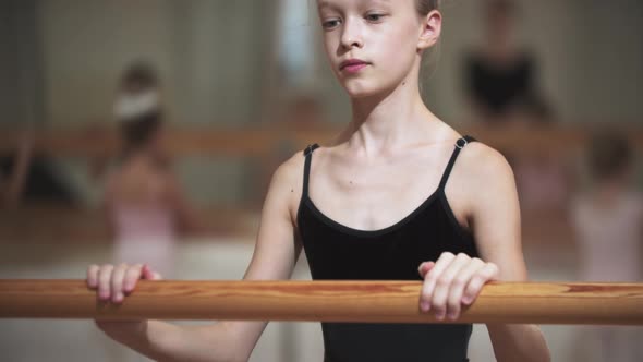 Skinny Little Girl Holding By a Stand in Ballet Studio