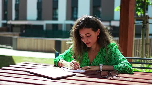 Caucasian Woman Drawing Ideas on a Notebook Outside Office