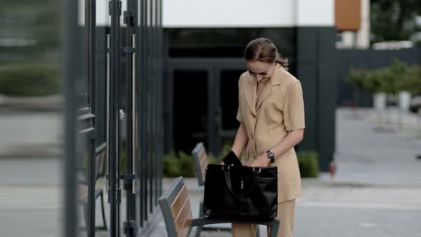 Beautiful professional businesswoman taking out documents from her bag near the office