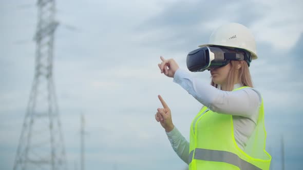 A Woman Electrician in Virtual Reality Glasses Moves Her Hand Simulating the Work with the Graphical