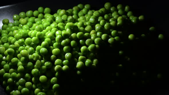 Fresh Peas Gyrating on Black Background