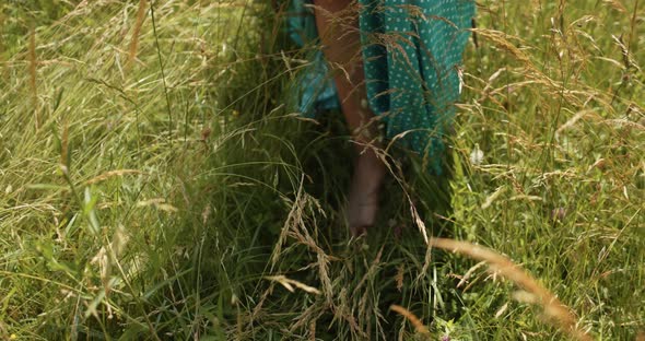 Girl Barefoot In A Long Dress Walking On The Grass