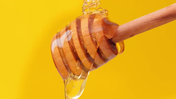 Close Up Fresh Fluid Honey Pouring and Flowing From Wooden Dipper Spoon