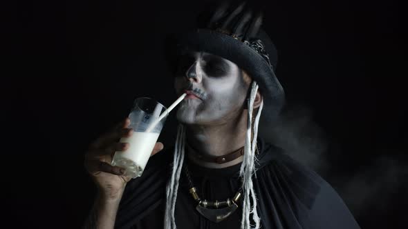 Scary Guy in Carnival Costume of Halloween Skeleton Looking at Camera, Drinks Milk From a Glass