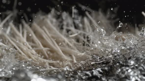 Throwing enoki mushroom into water. Slow Motion.