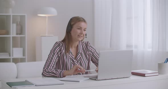 Young Female Lawyer Is Consulting Client Online By Video Call, Talking at Mic in Headphones and