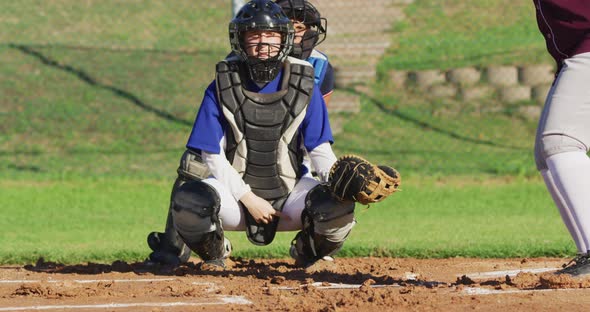 Caucasian female baseball player in catcher position catching ball on baseball field