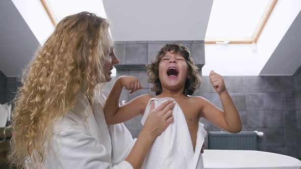 Boy Showing Arm Gestures How he is Strong while His Cute Blond Mother Wiping the Body