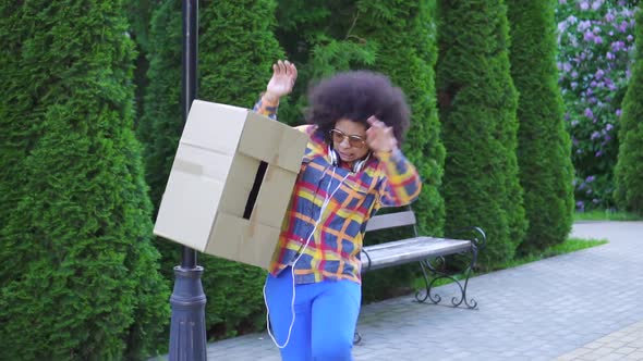 Positive African American Young Woman Courier or Delivery Man with African Hairstyle Drops Box