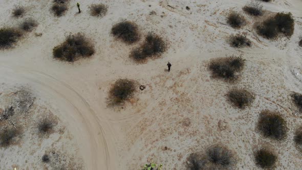 A Man walks slowly on his own through the barren lonley desert in Joshua Tree birdseye Drone Aerial,