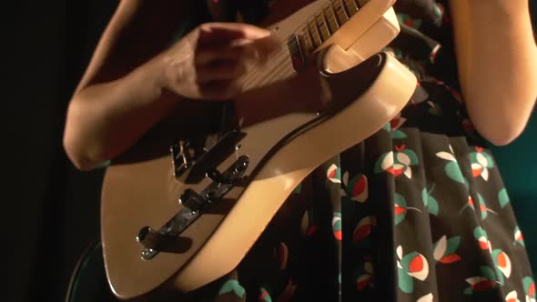 Female guitarist playing on stage at music festival	