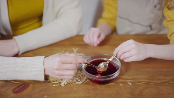 Unrecognizable Mother and Girl Dyeing Eggs for Easter