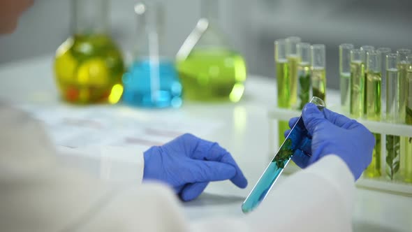 Biochemist Comparing Plants in Tubes With Green and Blue Liquids, Preservatives