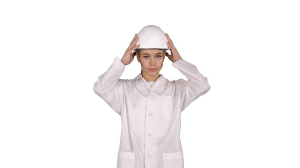 Woman engineer in white robe and white hard hat walking