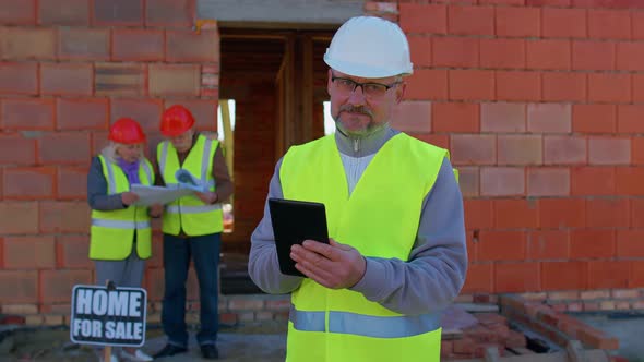 Builder Engineer Architect Operate with Digital Tablet to Control Working at Construction House Site