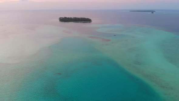 Aerial: flying over desert island tropical beach caribbean sea coral reef sunset