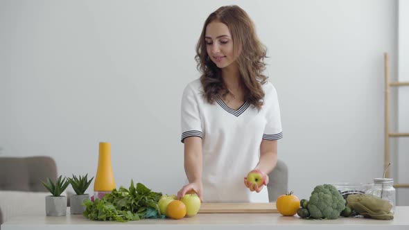 Young Skill Woman Puts Apples on the Table While Standing in Modern Kitchen